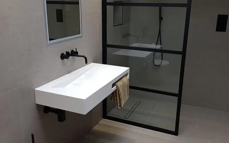 Bathroom with a wall-mounted basin, black fittings and a framed shower screen