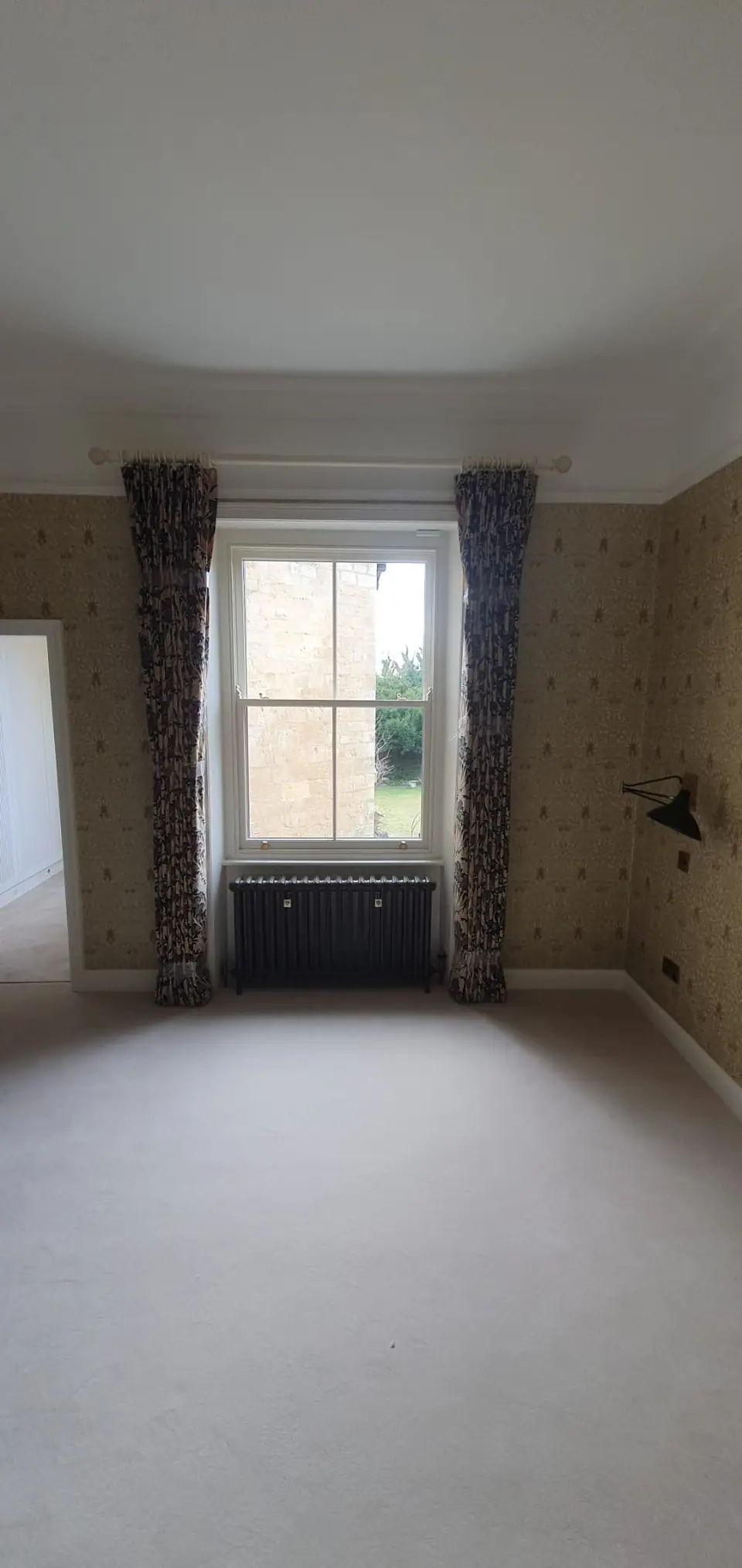 Cast iron column radiator under a sash window in a bedroom