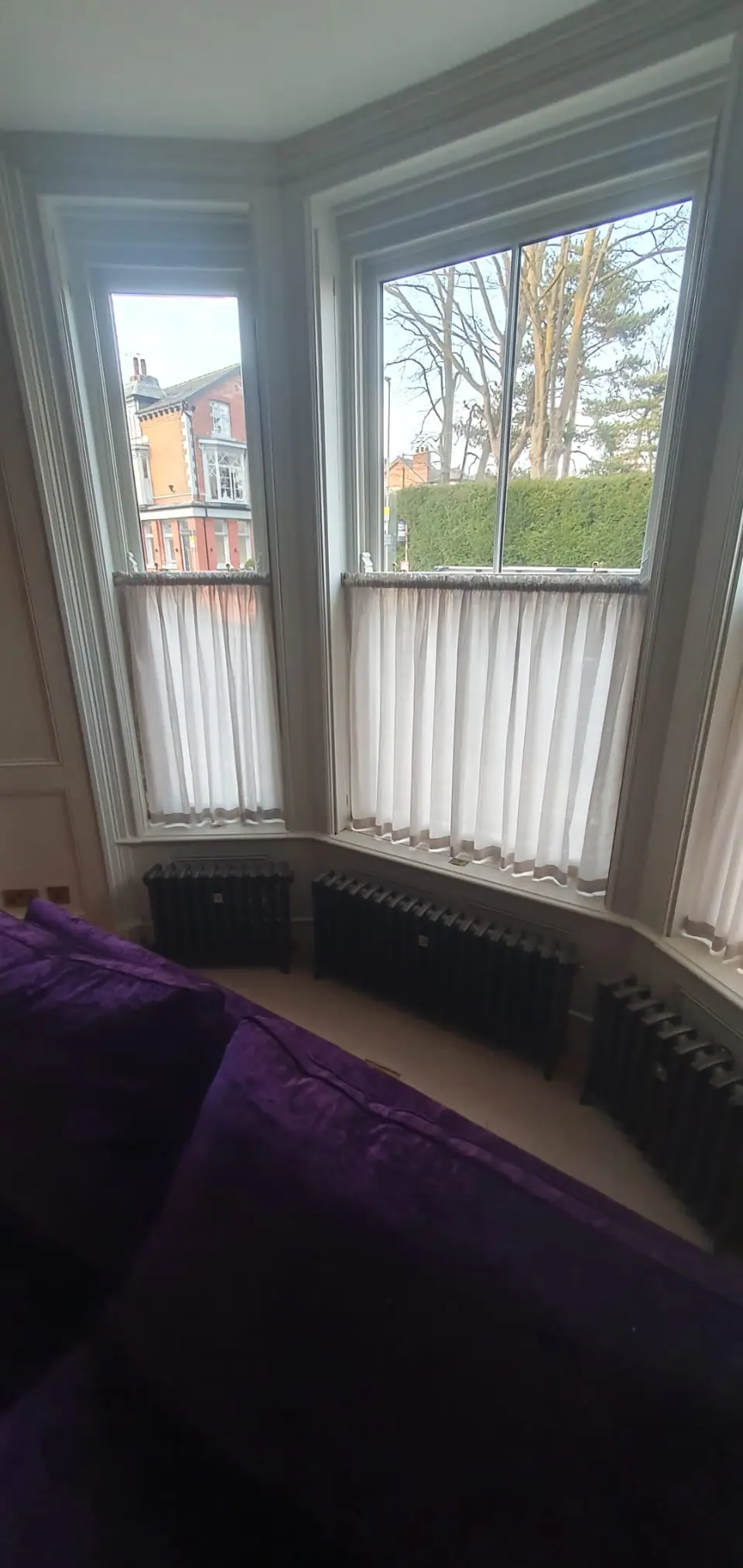 Column radiators fitted beneath a bay window in a period room